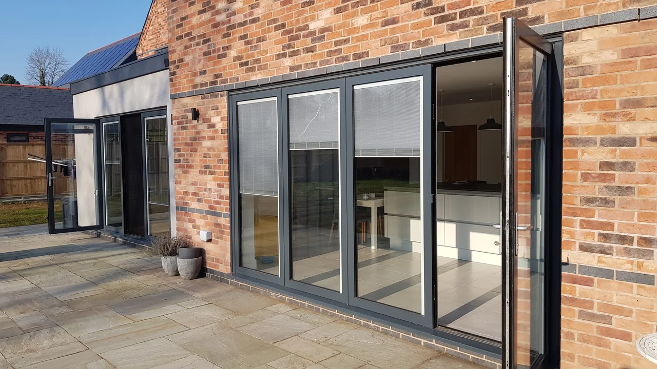 Charcoal OpenGlide doors across adjoining brick and rendered garden-facing openings