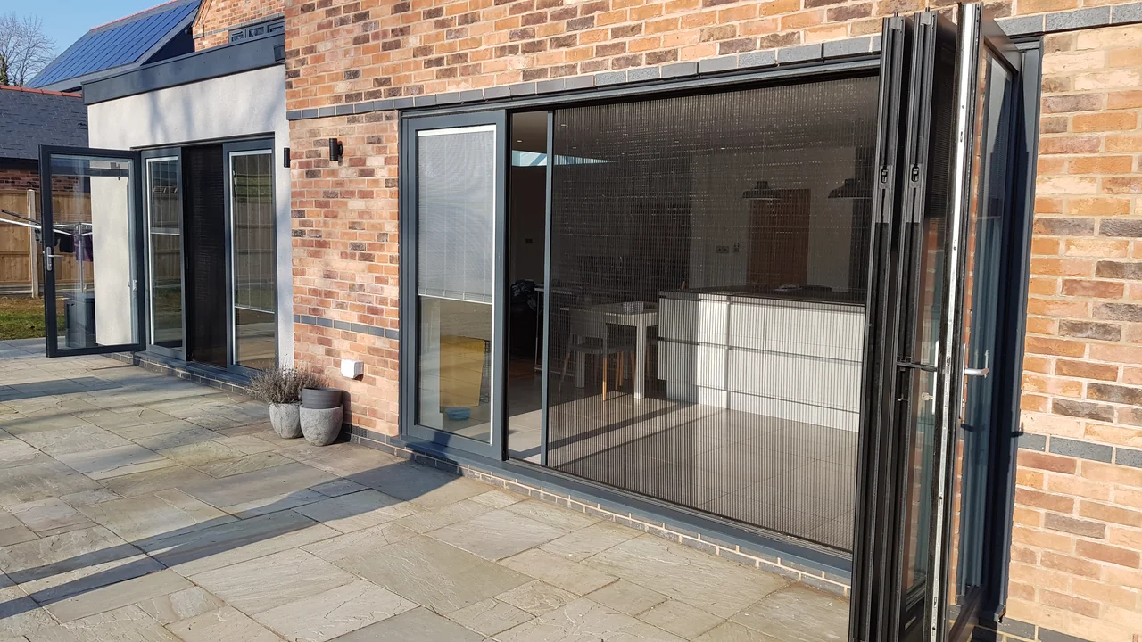 Pleated flyscreen extended across an opening beside gathered OpenGlide door panels